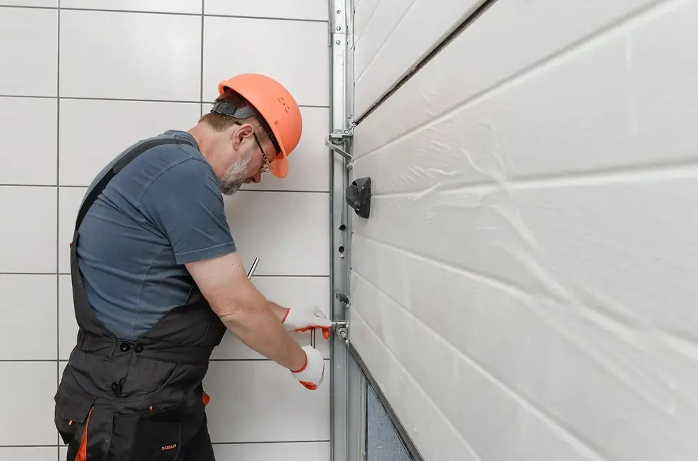 Technician tightening garage door track bolts