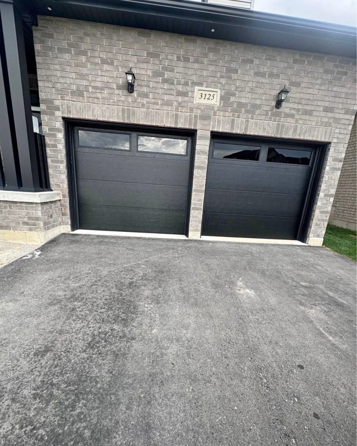 Double black garage doors on grey brick home